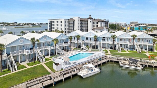 A waterfront hotel with multiple guest rooms, a central pool, and a dock with boats. - Waterfront 2BR Condo *Renovated 2025*  Marina Pool (Orange Beach)