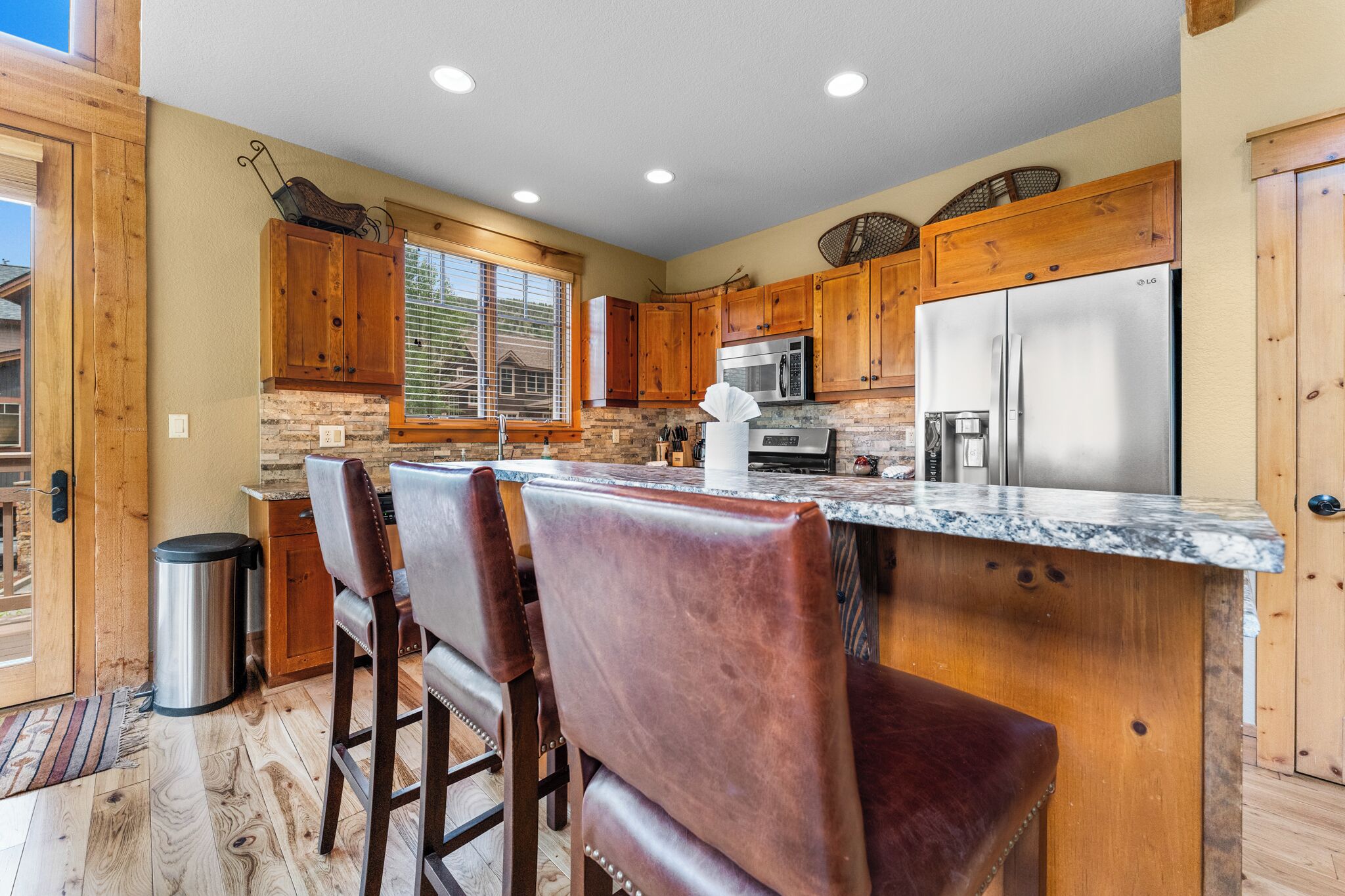 A kitchen with wooden cabinets, a stainless steel refrigerator, and a marble countertop.
