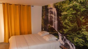A bedroom with a bed, yellow curtains, and a waterfall mural on the wall. - LE Massif - Appartement Avec vue Imprenable (La Bresse)