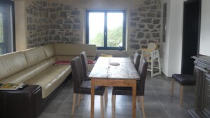 A dining area with a stone wall, a wooden table, and a leather sofa. - LE Massif - Appartement Avec vue Imprenable (La Bresse)