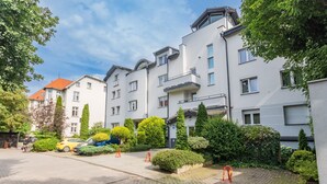 A residential building with multiple floors, balconies, and a paved driveway. - Molo Centrum by Grand Apartments (Sopot)