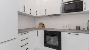 A modern kitchen with white cabinets, a built-in oven, a microwave, and a coffee maker. - Molo Centrum by Grand Apartments (Sopot)