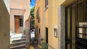 En smal gränd mellan byggnaderna, med en trädörr och ett fönster med galler.