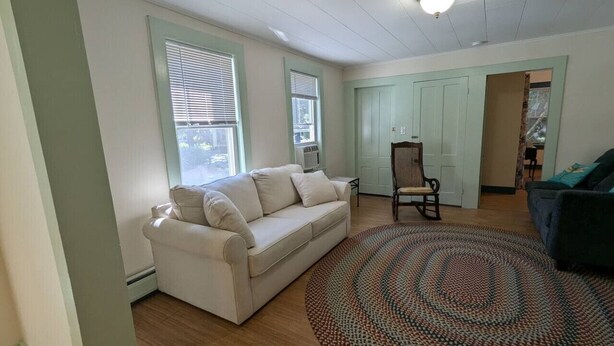 Un salon avec un canapé beige, un tapis à motifs et un plancher en bois.