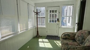 Une pièce avec un sol vert, une porte blanche et une fenêtre avec des stores.