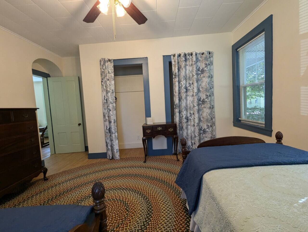 A bedroom with two beds, a dresser, a desk, and a ceiling fan.