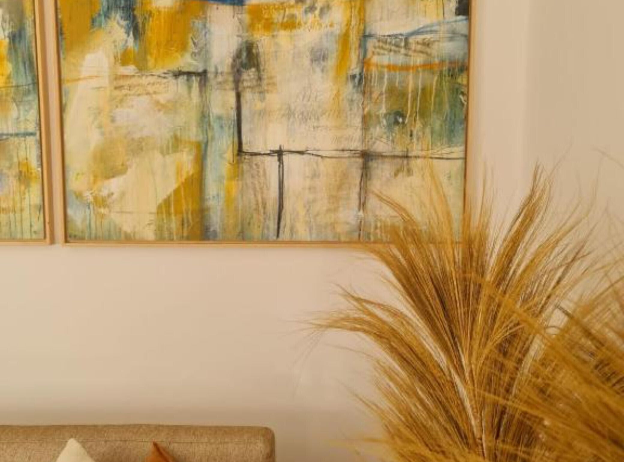 Deux tableaux abstraits aux couleurs chaudes, accrochés à un mur uni.