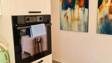 Een keuken met een moderne kookplaat, een handdoek aan de muur en abstracte kunst.