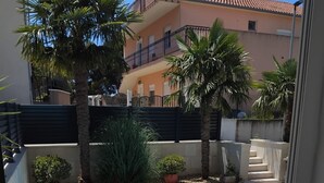 A residential building with a balcony, palm trees, and a black fence. - Villa Marija - Five Bedroom Villa with Terrace and Swimming Pool (Podstrana)