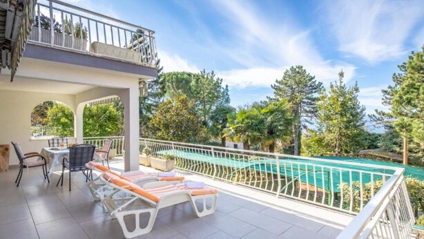 Un espacio al aire libre techado con piscina, sillas de descanso y una mesa.