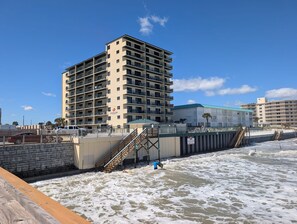 Ein mehrstöckiges Hotel mit Balkonen, einer Lage direkt am Strand und einer Treppe zum Strand.