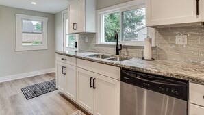 A modern kitchen with white cabinets, a stainless steel dishwasher, and a granite countertop. - Charming Pepin Home Near Mississippi River! (Pepin)