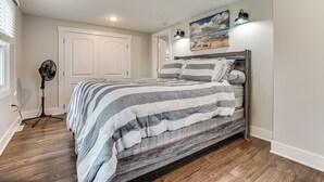 A bedroom with a bed, a standing fan, and a door. - Charming Pepin Home Near Mississippi River! (Pepin)