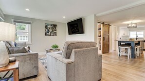 A modern living room with a sofa, a coffee table, and a lamp. There is a kitchen area with a dining table and chairs. - Charming Pepin Home Near Mississippi River! (Pepin)