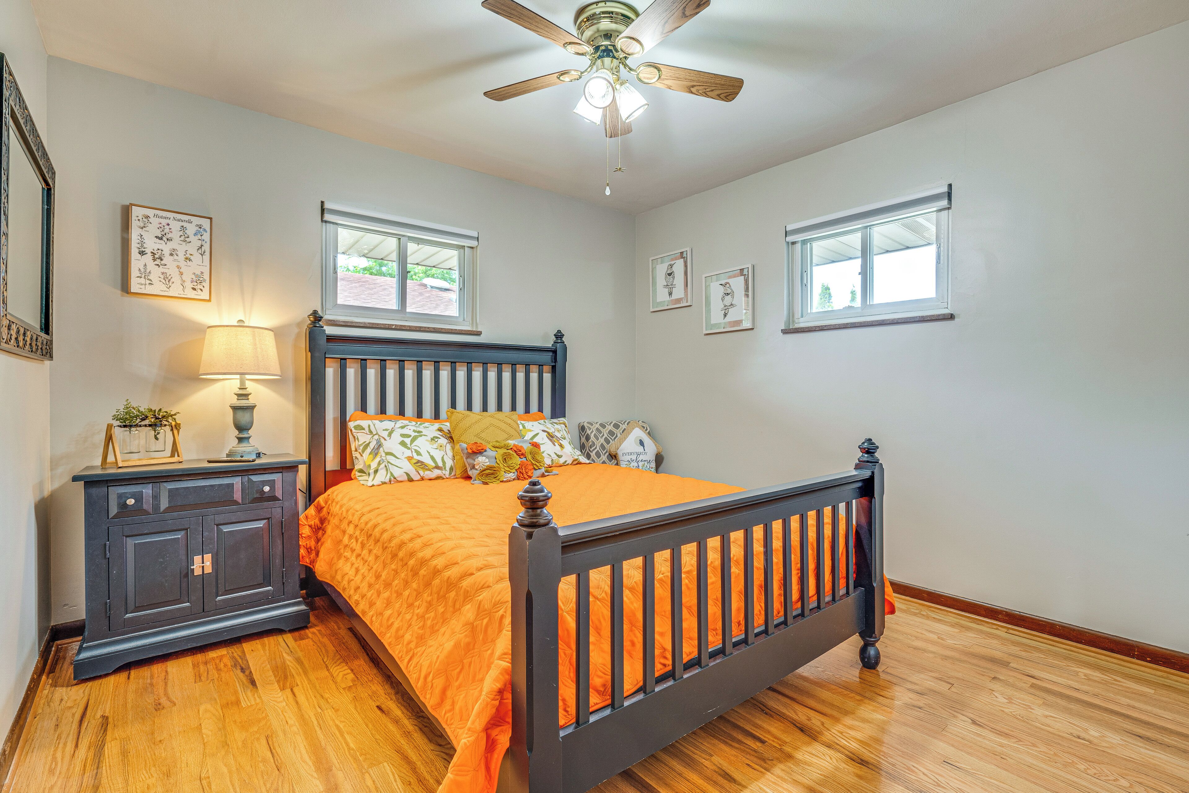 A bedroom with a wooden bed, a nightstand, a lamp, and framed pictures on the wall.