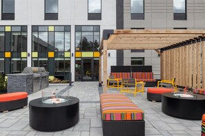 An outdoor patio area with seating, a fire pit, and a barbecue station. - Home2 Suites By Hilton Kitchener (Kitchener)