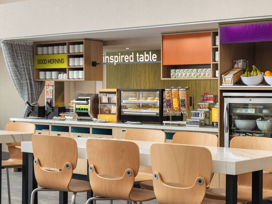 A modern cafe with a self-service counter, seating area, and various food and drink options.