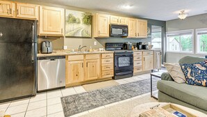 A kitchen with wooden cabinets, a black refrigerator, a dishwasher, a microwave, and an oven. - 2 MI to the Lake: Mecosta Getaway with Fire Pit! (Mecosta)