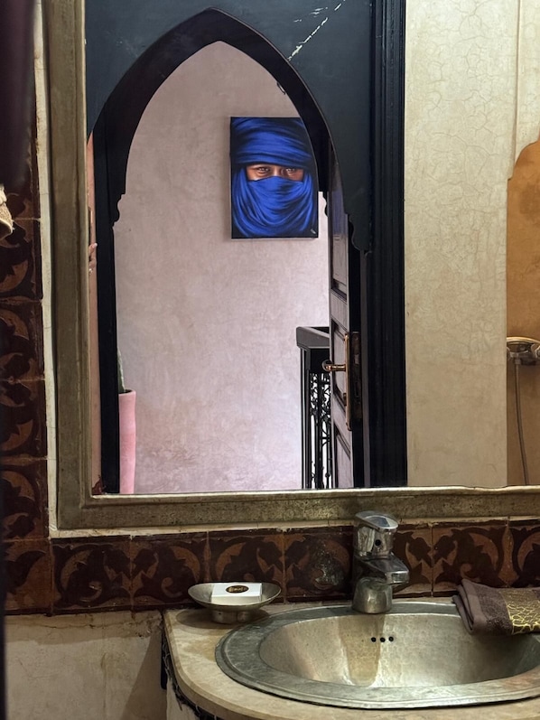 A bathroom with a large mirror, a sink, and a towel rack.