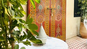 A traditional Moroccan interior with a patterned door, a white table with a decorative bowl, and a potted plant. - Riad Dar Serenity (Marrakech)
