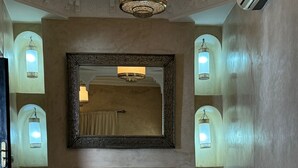 A bedroom with a large bed, a fireplace, and wall-mounted sconces. - Riad Dar Serenity (Marrakech)