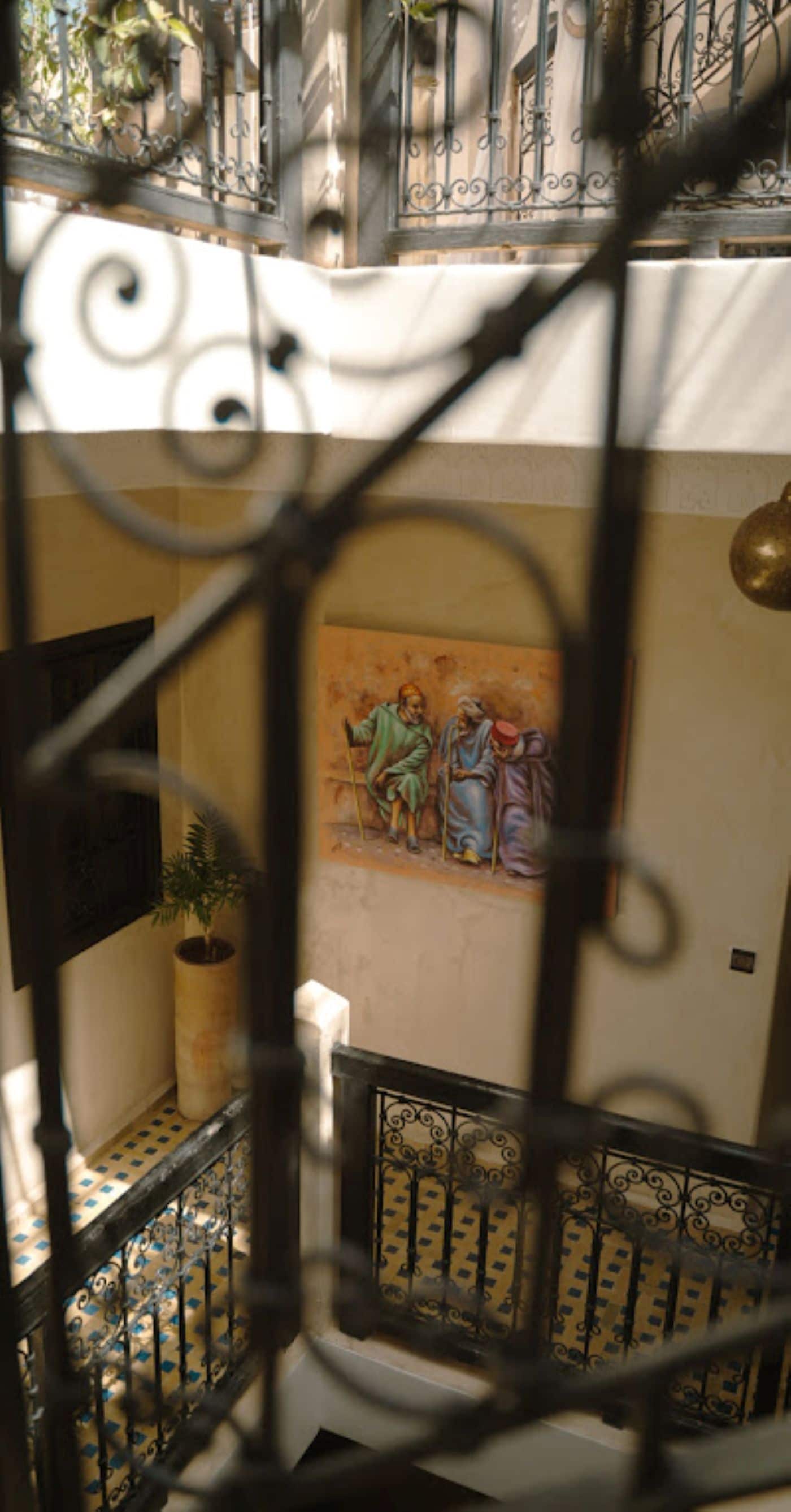A staircase with ornate metal railings and a mural on the wall.