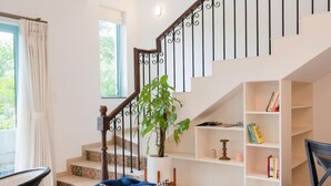 A living room with a blue sofa, a staircase with a white railing, a potted plant, and a bookshelf. - 3bhk Villa w Private Pool Assagao Villa C Leste (Parra)