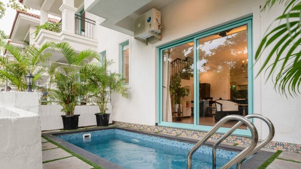 A swimming pool with a tiled edge, surrounded by potted plants and a white wall with a blue trim. - 3bhk Villa w Private Pool Assagao Villa C Leste (Parra)