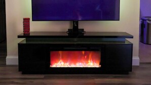 Un televisor de pantala plana fixat a un moble negre amb una llar de foc integrada a la part inferior.