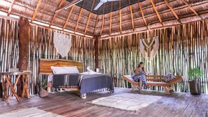 A room with a bed, a bench, a potted plant, and a ceiling fan. - Jungla & Estrellas (Coba)