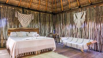 Una habitación con una cama, un diván y una mesita con una planta.