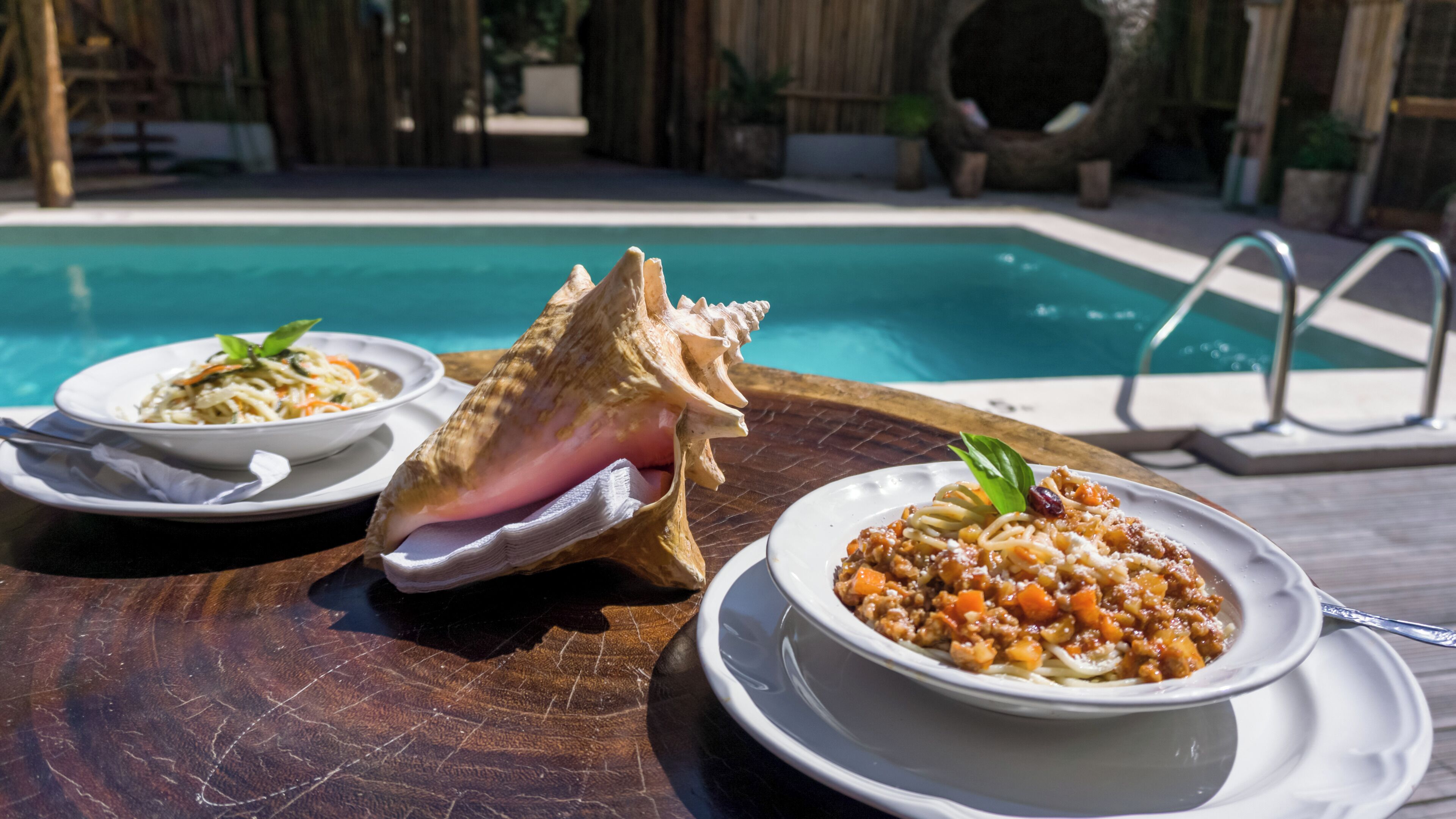 Una mesa de comedor con dos platos de pasta y una concha marina grande.
