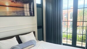 Une chambre d’hôtel avec un grand lit, un tableau au mur et une vue sur l’extérieur par une fenêtre.
