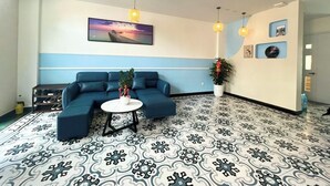 Un espace de détente moderne avec un canapé d’angle bleu, une table ronde et des plantes décoratives.