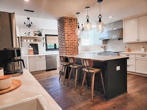 Una cocina moderna con una isla central, taburetes de bar e iluminación colgante.