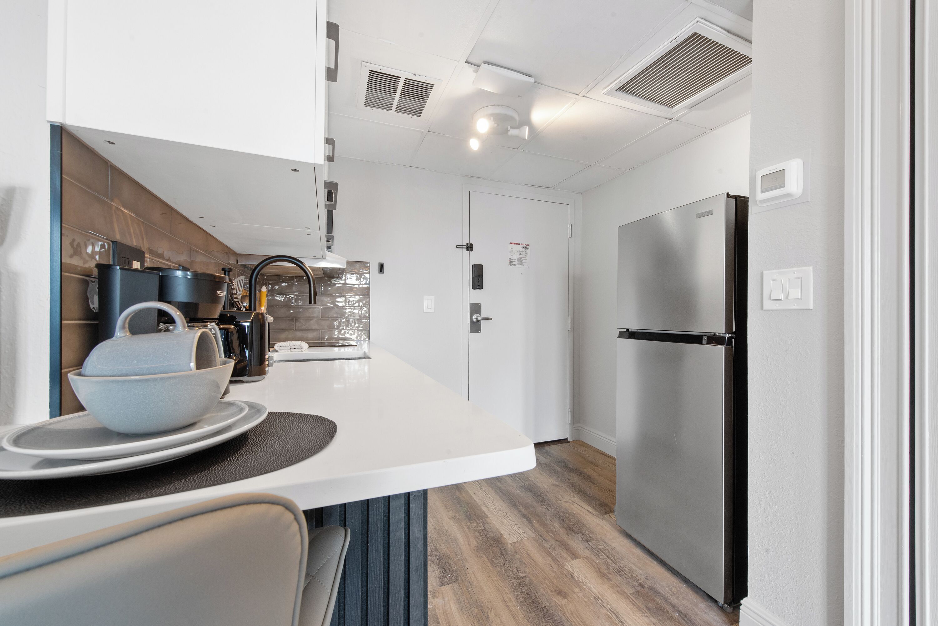 Una cocina moderna con encimera blanca, electrodomésticos de acero inoxidable y suelo de madera.