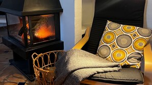 A cozy room with a fireplace, a wicker chair, and a patterned cushion. - Lovely 10-bed Villa With Private Pool & Garden (Cacin)