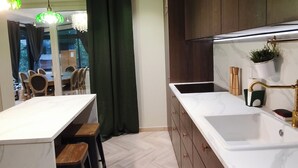 Cuina moderna amb taulell de marbre, armaris de fusta i zona de menjador amb cadires i taula.