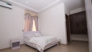 Een slaapkamer met een bed, nachtkastje, airconditioning en een kledingkast.