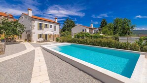 A poolside view of a villa with a clear blue pool, stone pathway, and surrounding greenery. - Holiday house RURAL HOME FRANE (Kornić)
