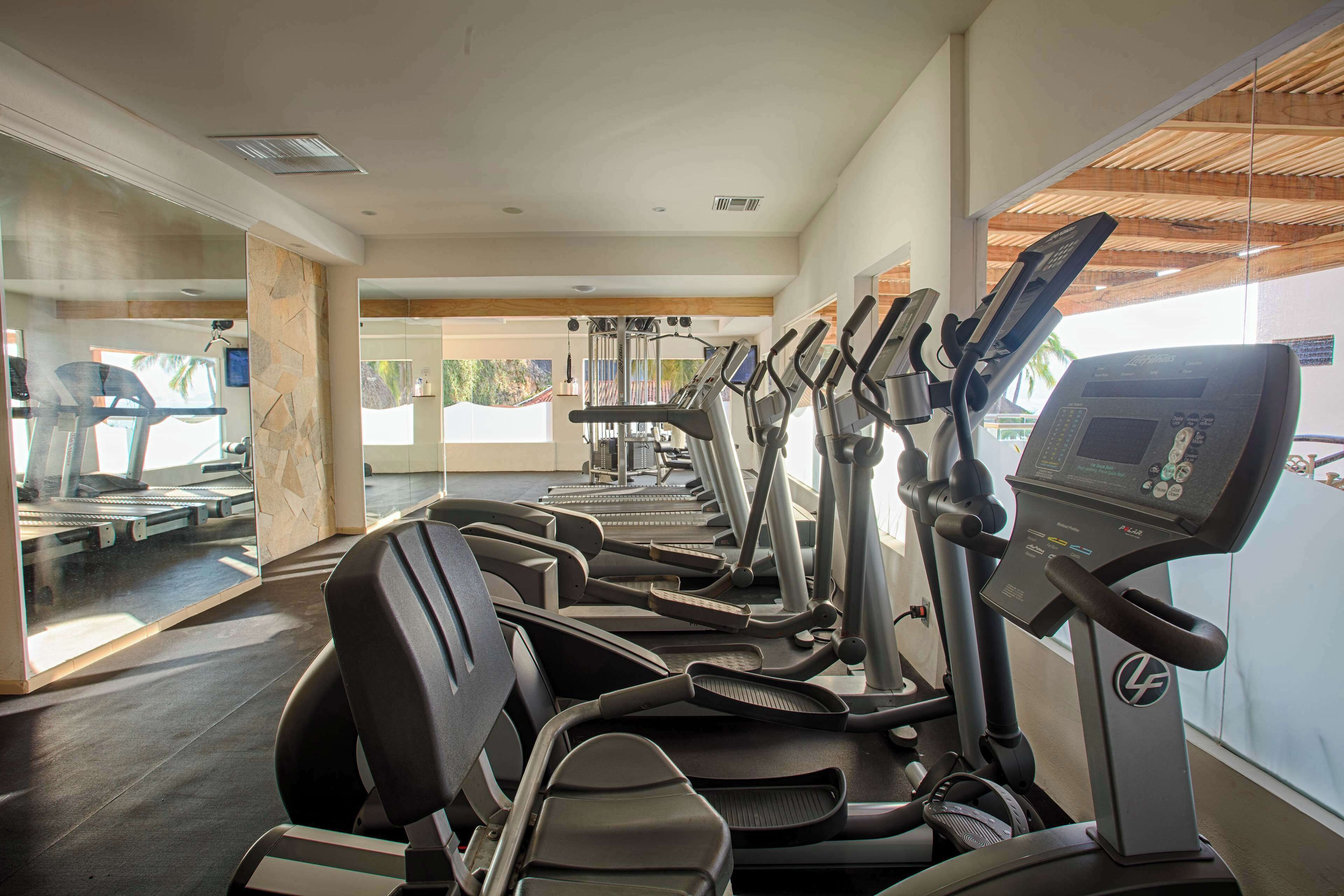 Ein Fitnessstudio mit mehreren Laufbändern und Trainingsgeräten.