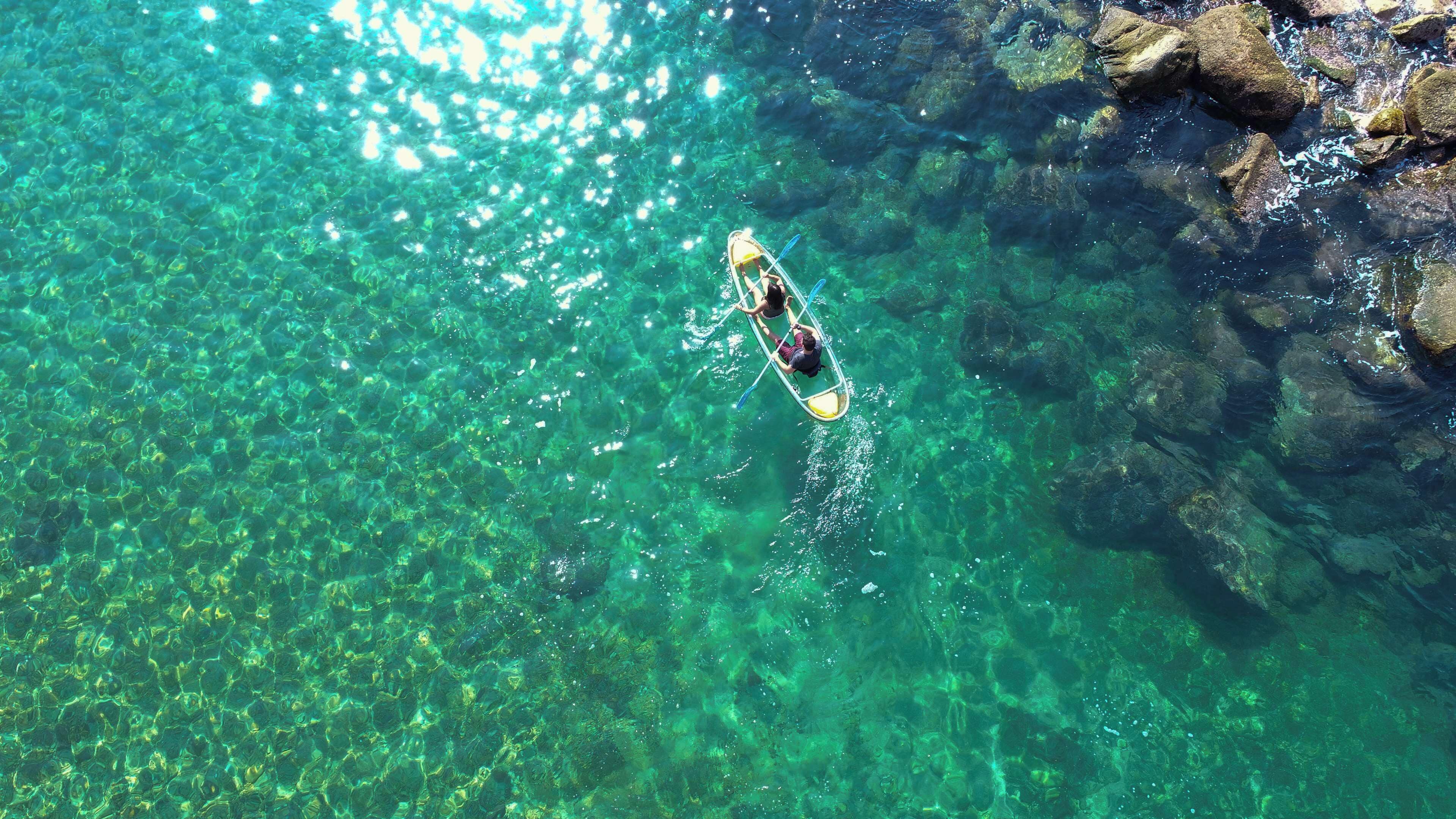 Vista despejada de un kayak sobre aguas tranquilas y transparentes, rodeado de rocas.