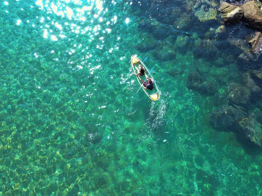 Vista despejada de un kayak sobre aguas tranquilas y transparentes, rodeado de rocas.