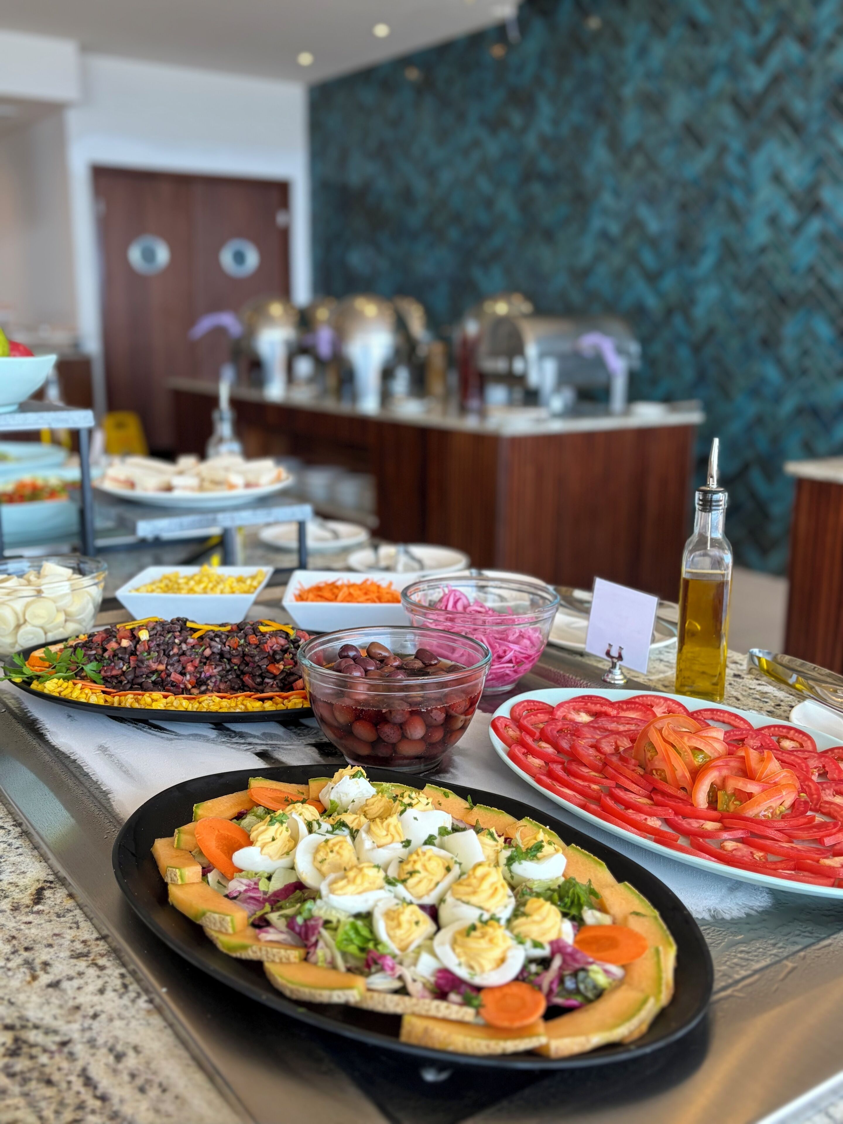 Een buffet met diverse gerechten, waaronder salades, een fruitplateau en een kaasplank.