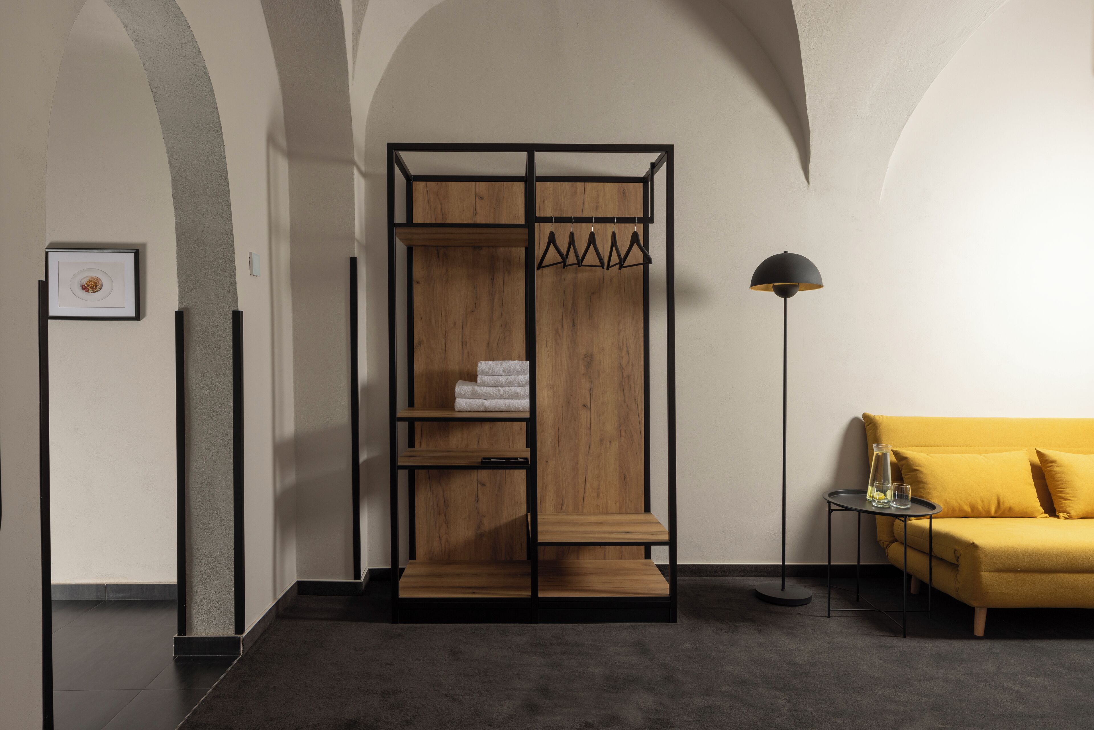 Ein modernes Zimmer mit einem Holzschrank, einem kleinen Tisch mit einem Glas und einem gelben Sofa.