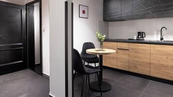 A modern kitchen with a black marble backsplash, a wooden countertop, and a round table with two chairs.