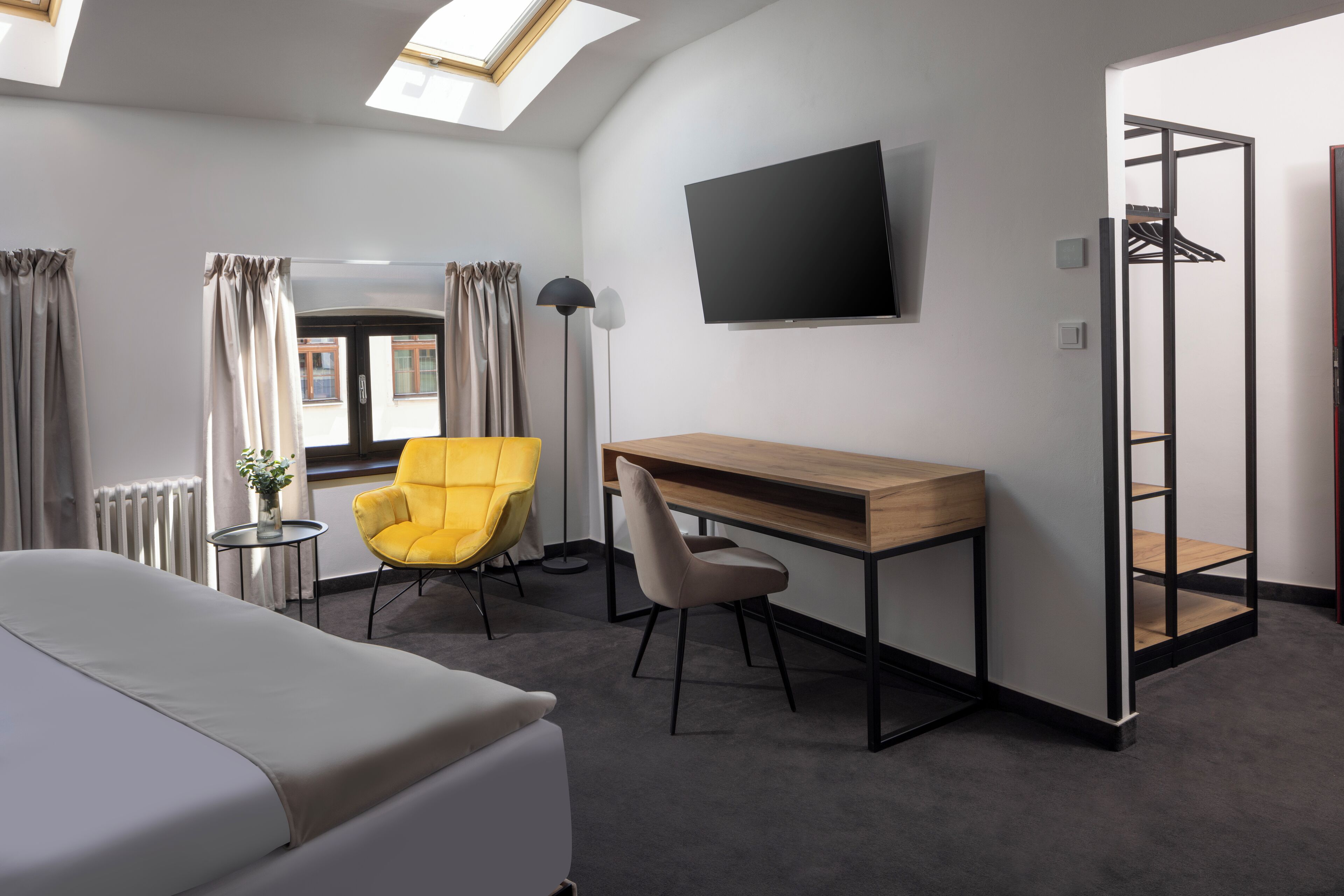 Une chambre d’hôtel équipée d’un lit, d’un bureau, d’une chaise, d’une télévision et d’une armoire.