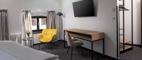 Une chambre d’hôtel équipée d’un lit, d’un bureau, d’une chaise, d’une télévision et d’une armoire.