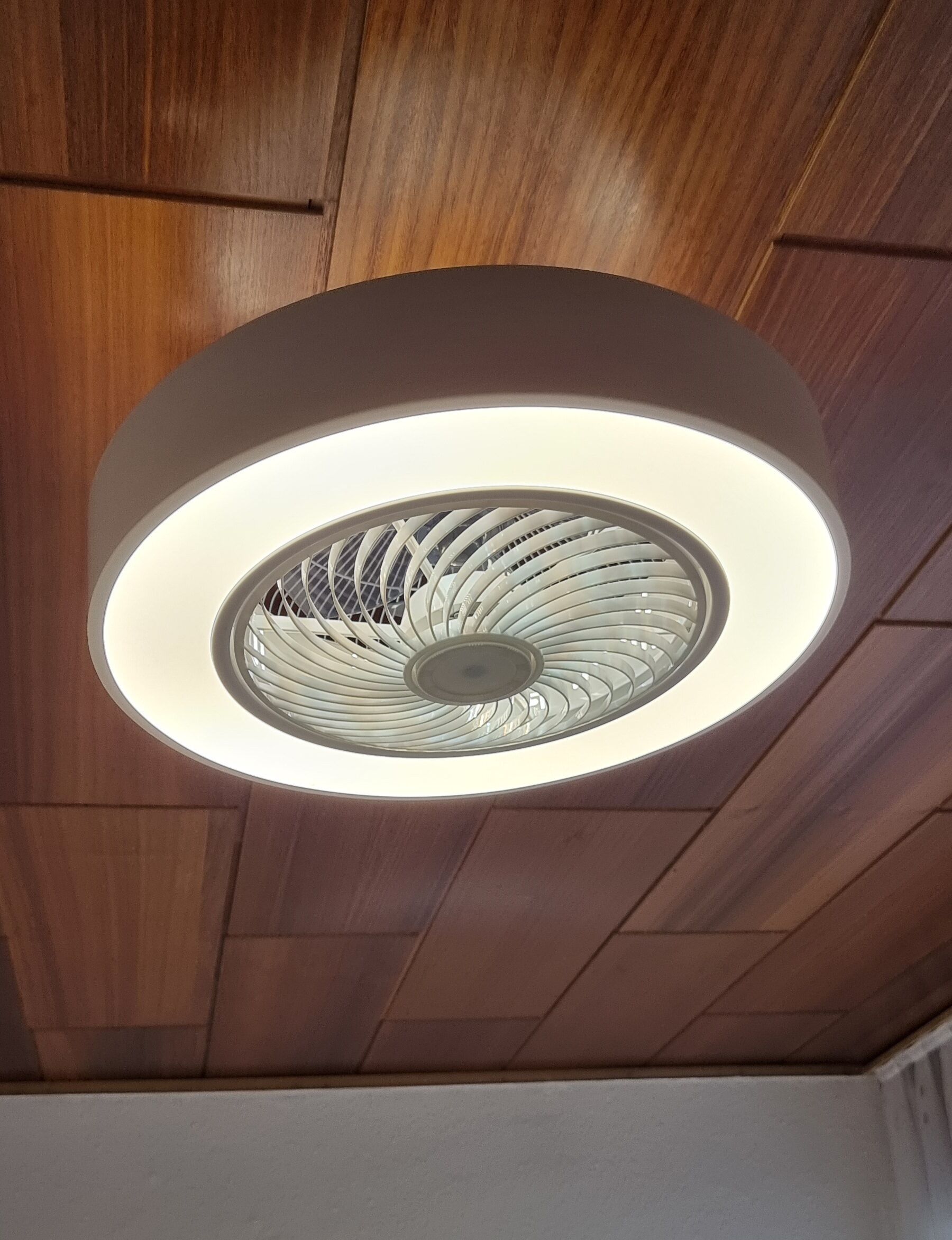 A ceiling with a circular light fixture and wooden paneling.