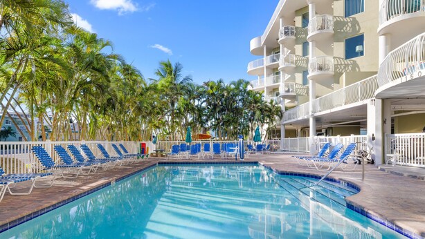 A swimming pool with lounge chairs and palm trees.